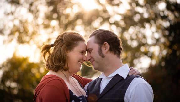 A man an a woman looking into each others eyes as they lean their heads on each other whilst facing