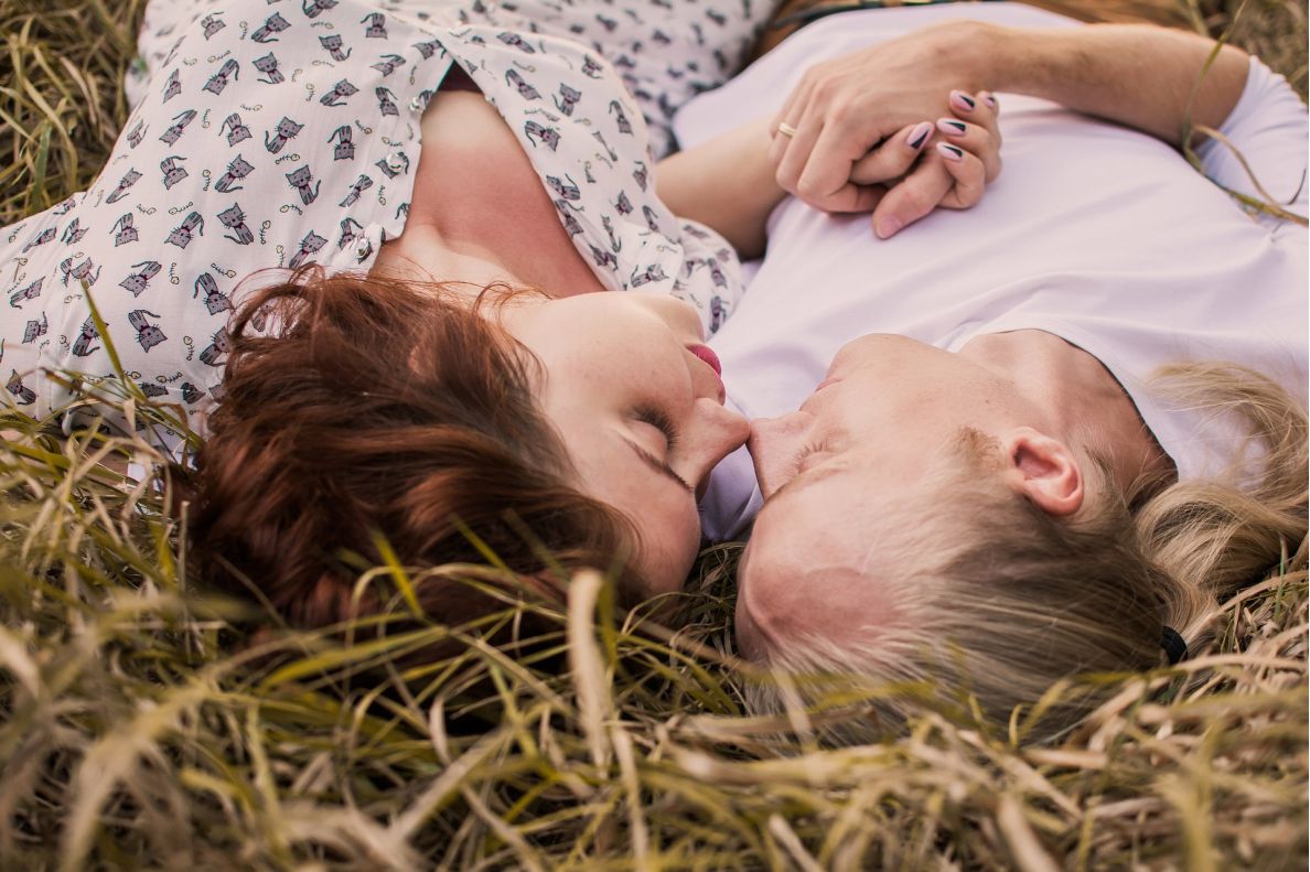 Two lovers lying in the grass looking into each others eyes