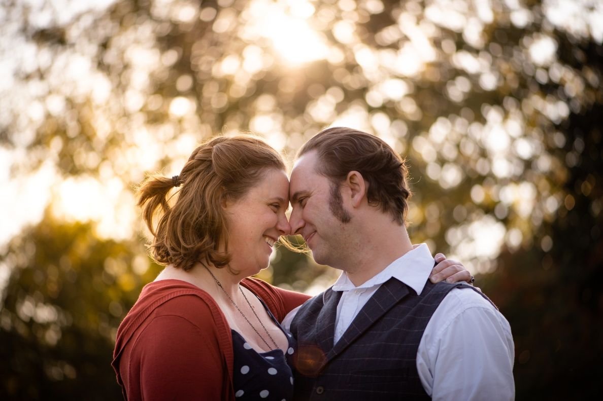 A man an a woman looking into each others eyes as they lean their heads on each other whilst facing