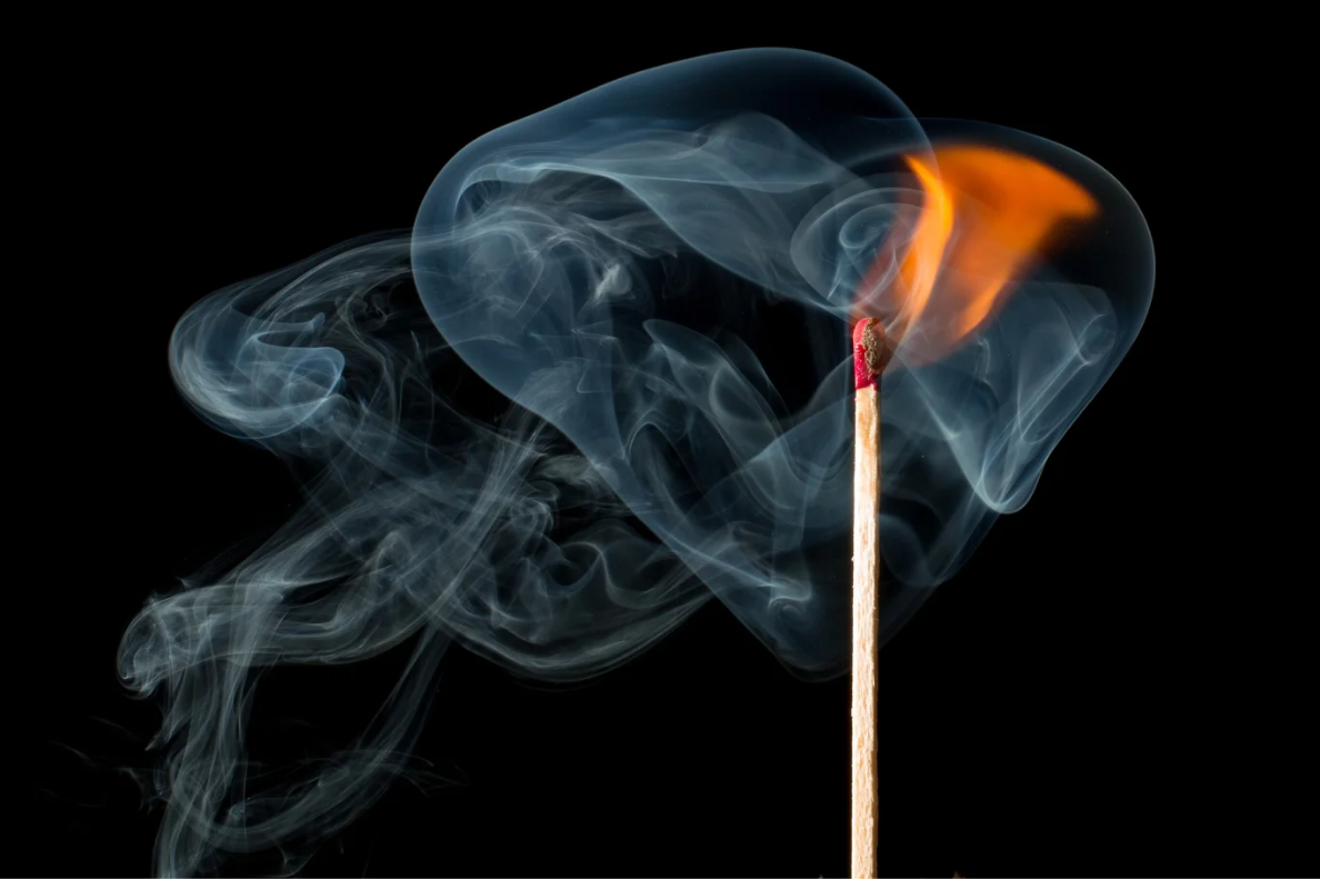 A match with smoke coming off the end in a dark room