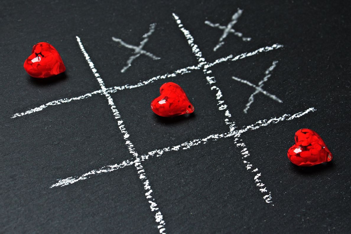 Noughts and Crosses on a chalk board with hearts instead of noughts