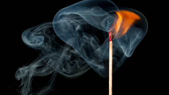 A match with smoke coming off the end in a dark room